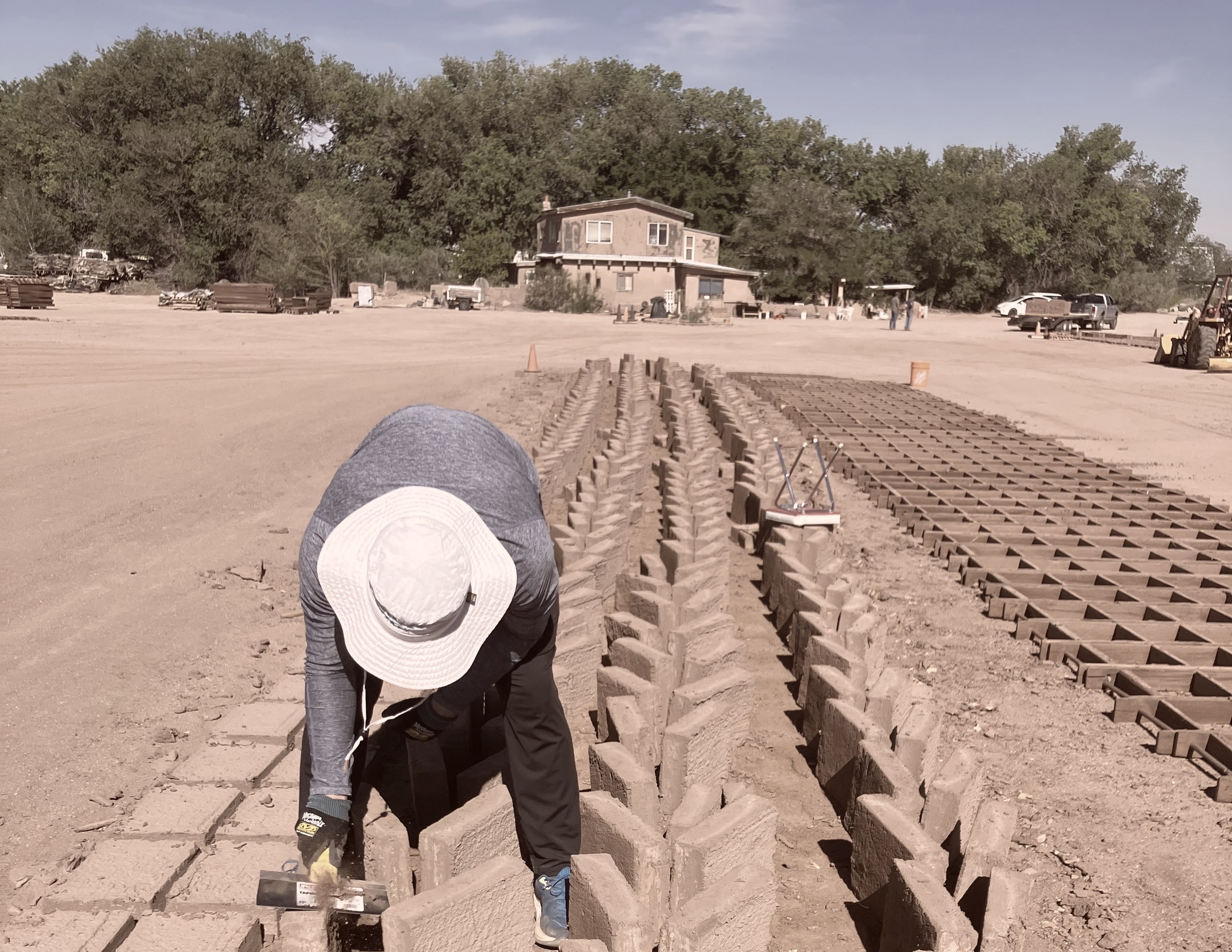 Hand-tooling and scraping fresh adobe blocks in the mold rows